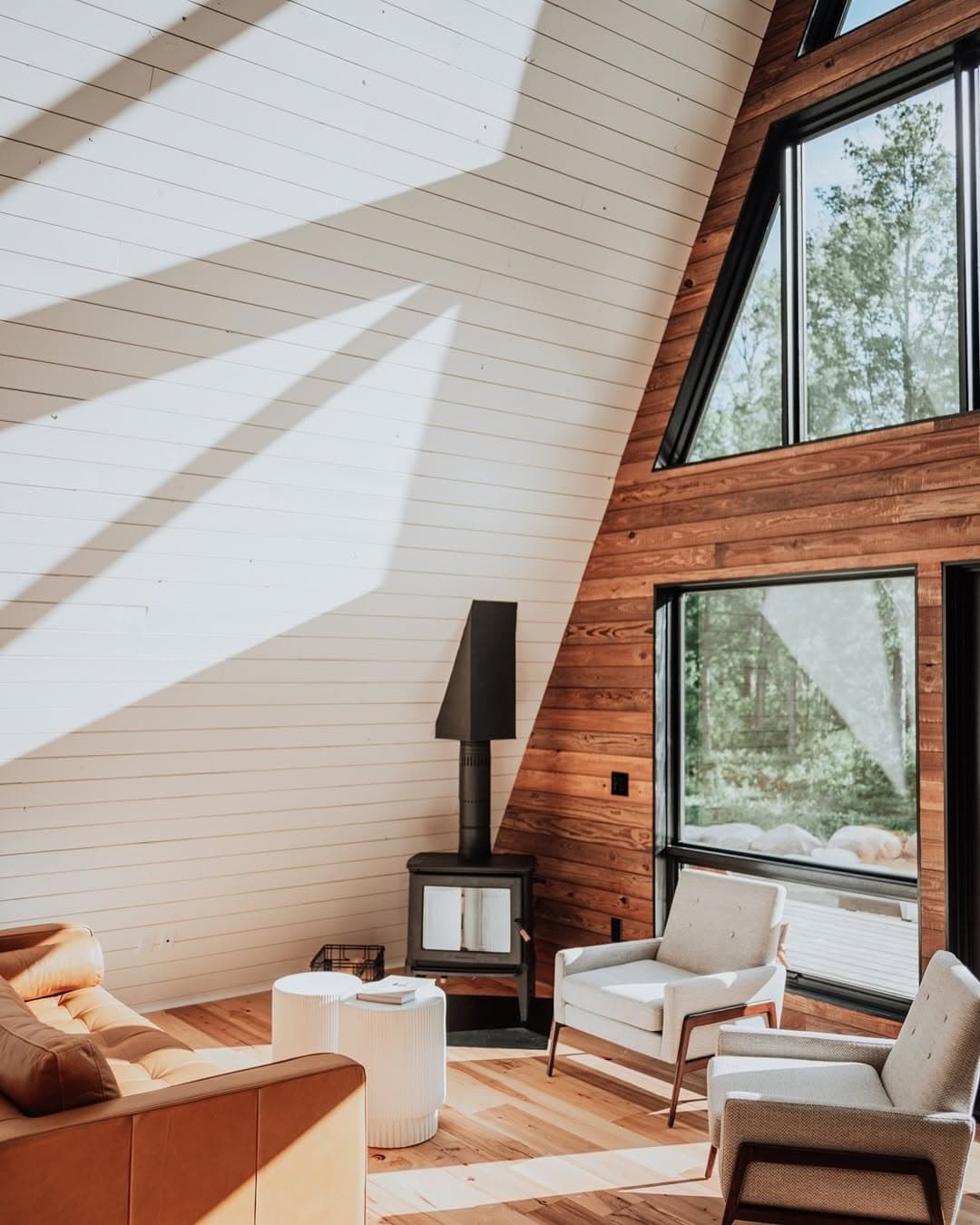 Bright, sunlit A-frame interior with modern fireplace and orange sofa
