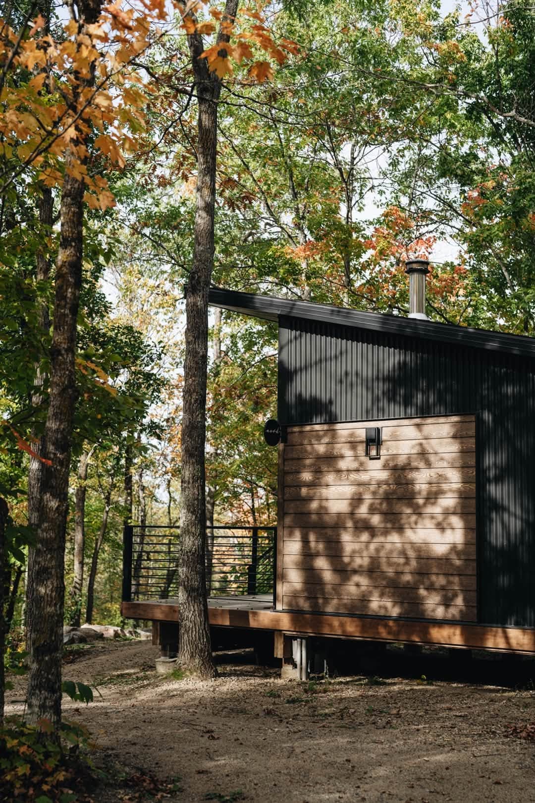 Modern tiny cabin elevated on deck with autumn foliage