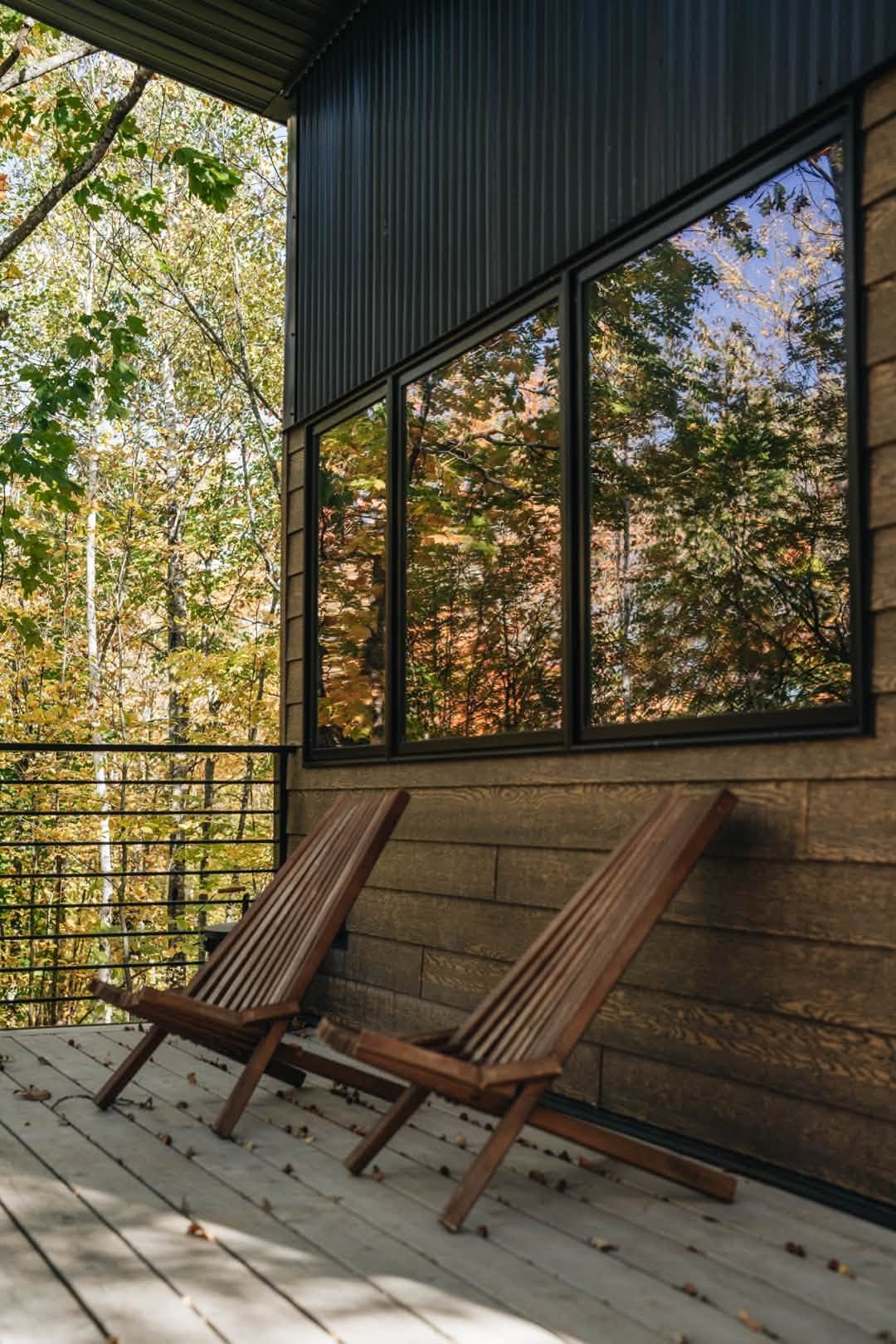 Deck with lounge chairs and large windows overlooking forest
