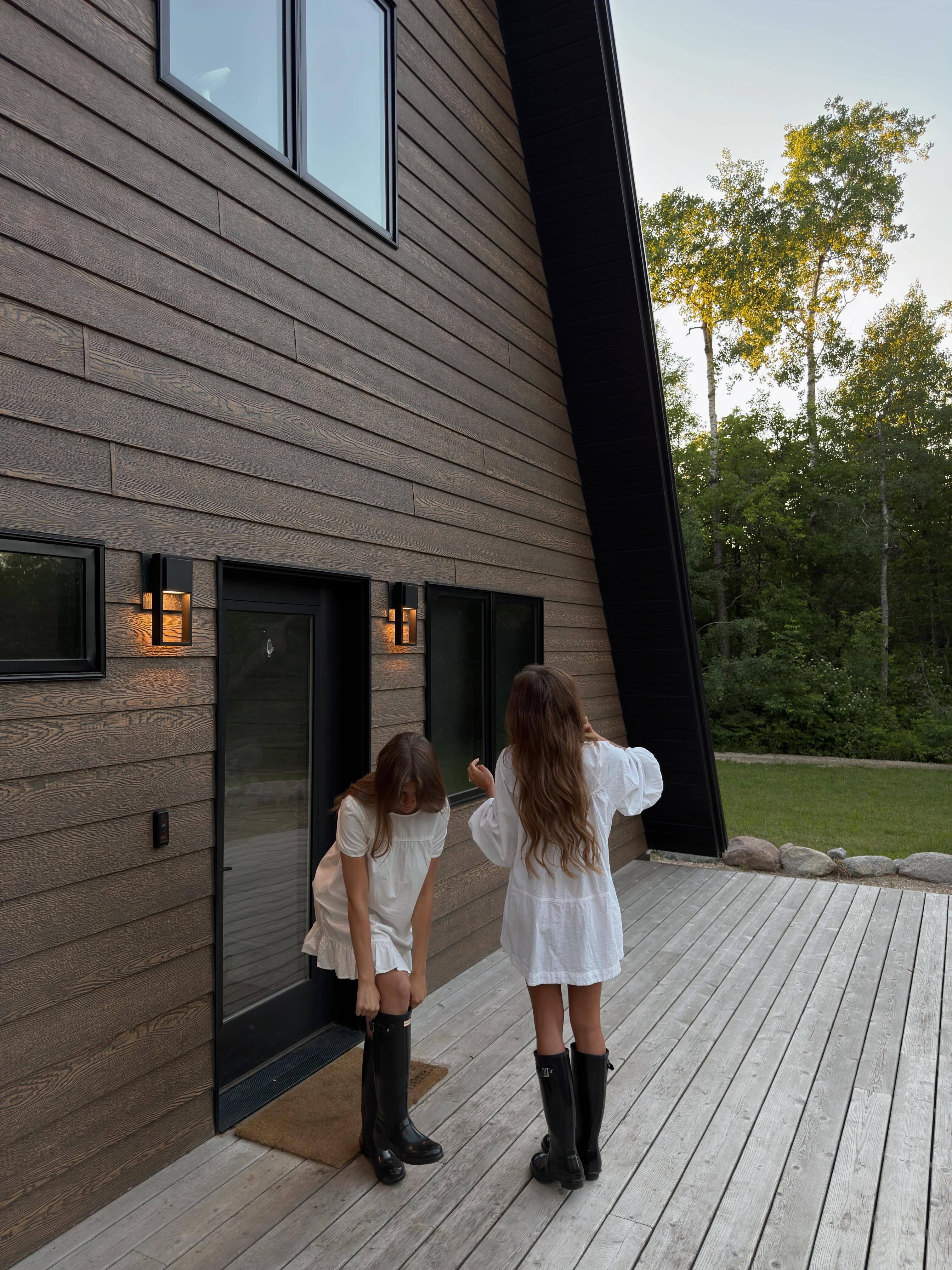 Two women on the deck of the A-frame cabin at dusk with warm lighting