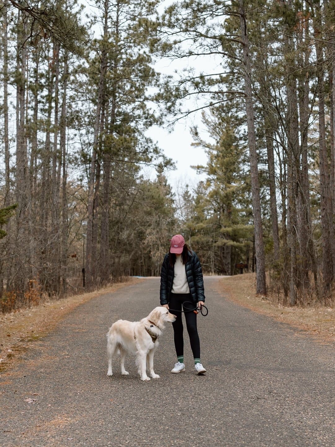 Mary standing on a forest road with pine trees